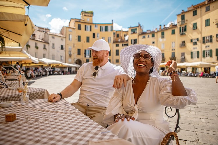 A man and a woman sitting at a table in a restaurant in a European square