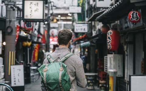 A person with a backpack walking through a market street