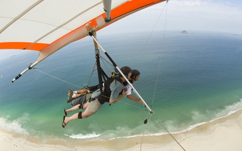 Two people paragliding above a beach