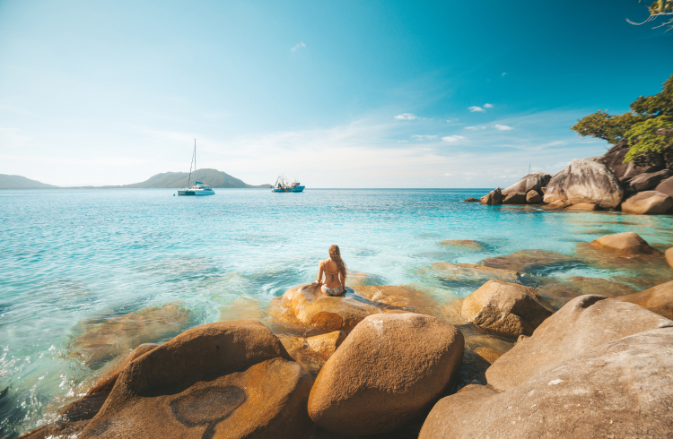 A woman sitting in front of bright blue water in Queensland