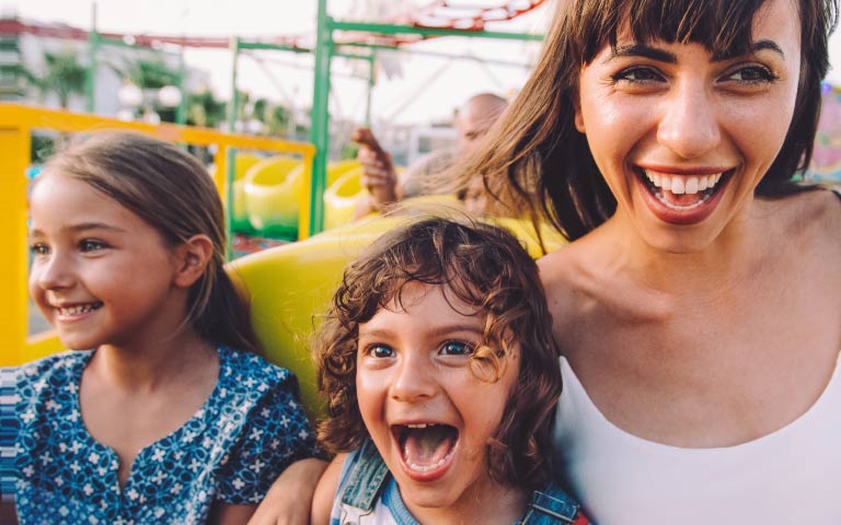 A woman and two children smiling on a rollercoaster