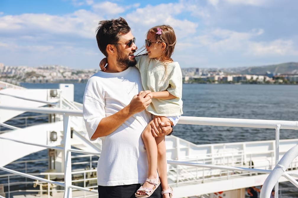 A father and daughter smiling in front of water