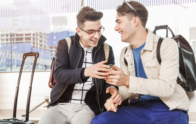 Two people with luggage smiling and looking at a phone